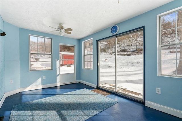 doorway with ceiling fan, baseboards, finished concrete floors, and a textured ceiling