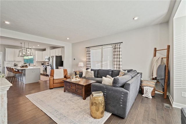 living area featuring visible vents, wood finished floors, recessed lighting, and baseboards