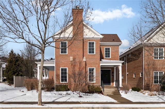 view of front of home featuring fence, a chimney, and brick siding