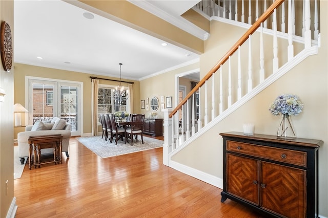 entryway with an inviting chandelier, crown molding, stairway, and wood finished floors