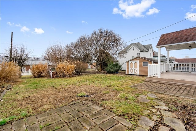 view of yard featuring a shed, fence, a deck, and an outdoor structure