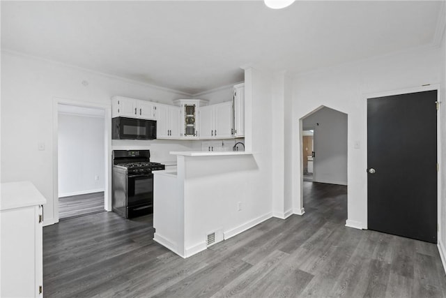 kitchen with arched walkways, glass insert cabinets, light countertops, black appliances, and white cabinetry