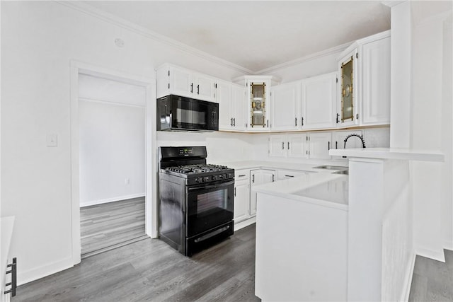 kitchen featuring a sink, white cabinetry, light countertops, black appliances, and glass insert cabinets
