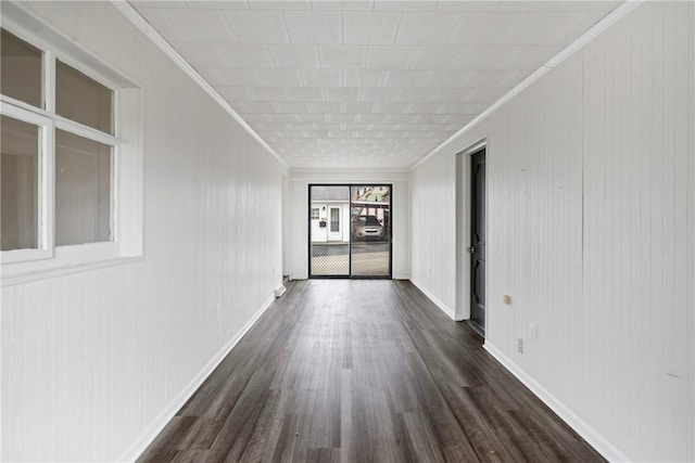 empty room with baseboards, dark wood finished floors, and crown molding