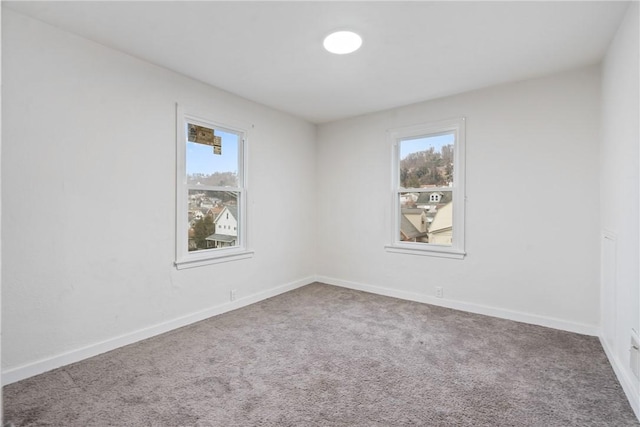 carpeted empty room featuring baseboards