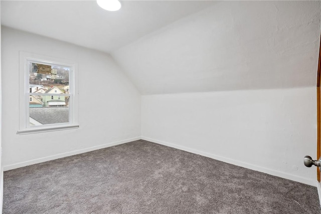 additional living space with lofted ceiling, baseboards, and dark colored carpet
