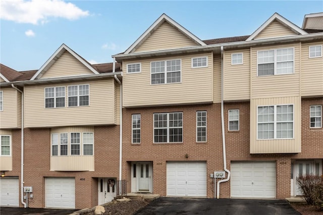 multi unit property featuring driveway, an attached garage, and brick siding