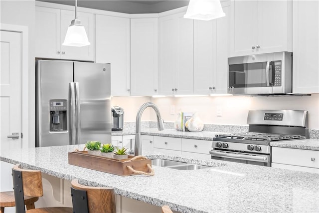 kitchen featuring pendant lighting, stainless steel appliances, a breakfast bar, and white cabinets