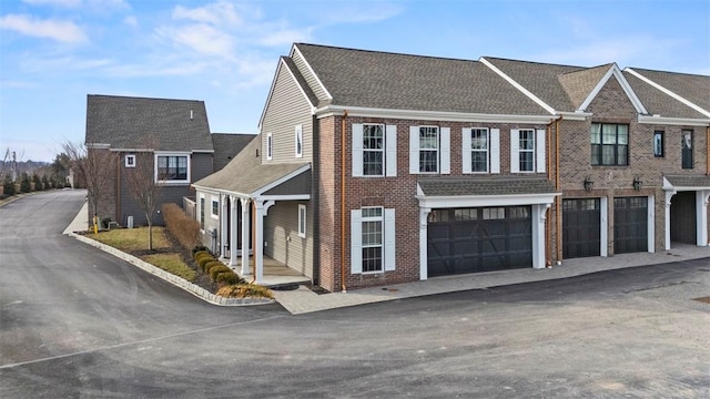 view of front facade with a garage, driveway, brick siding, and a shingled roof