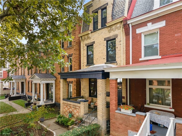 exterior space featuring roof with shingles, mansard roof, and brick siding