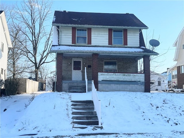 view of front of home with covered porch, brick siding, and fence