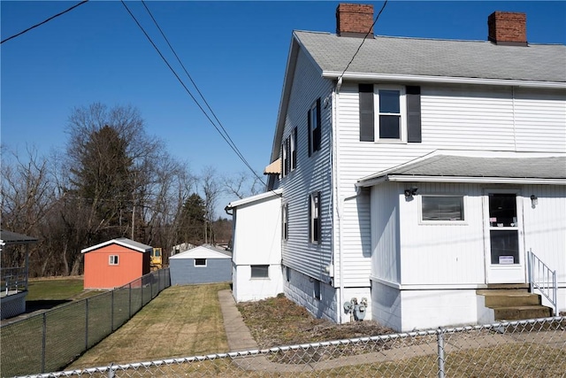 view of front of property with entry steps, a chimney, roof with shingles, fence private yard, and a front yard