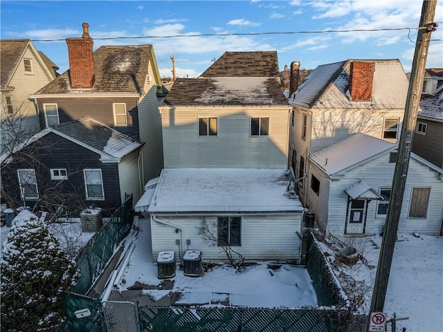 exterior space featuring fence private yard, a residential view, a chimney, and central air condition unit