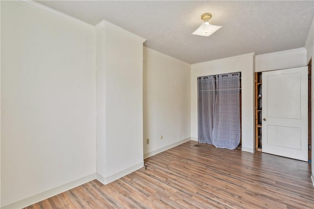 unfurnished room featuring ornamental molding, wood finished floors, and baseboards