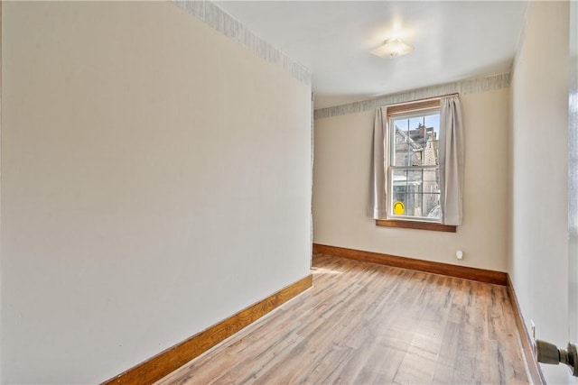 spare room featuring light wood finished floors and baseboards