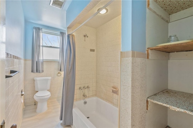 full bathroom with toilet, a wainscoted wall, visible vents, tile walls, and shower / bath combo