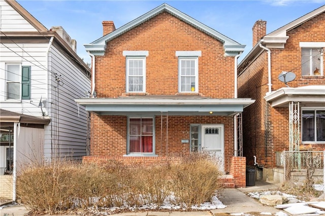 traditional-style home featuring a chimney and brick siding