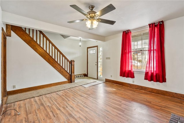 entrance foyer featuring visible vents, ceiling fan, wood finished floors, baseboards, and stairs