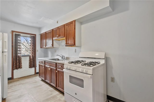 kitchen featuring light countertops, brown cabinetry, a sink, white appliances, and baseboards