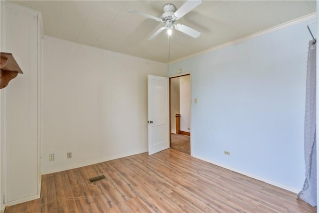 empty room featuring light wood finished floors, visible vents, ornamental molding, and a ceiling fan