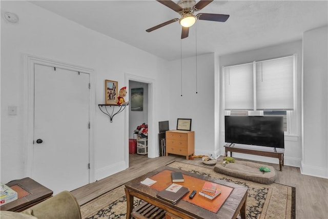 living room featuring ceiling fan, light wood-style flooring, and baseboards