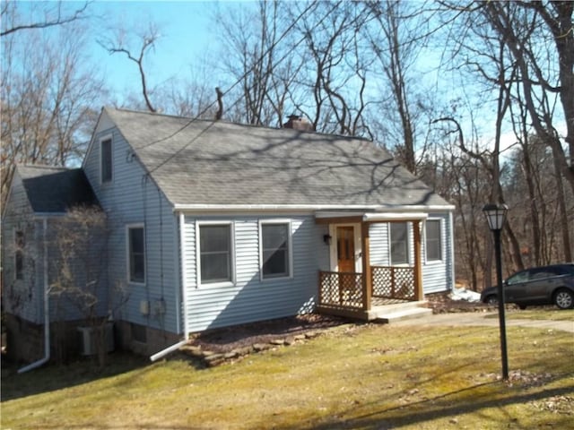 view of front of home featuring a chimney, a front lawn, cooling unit, and roof with shingles