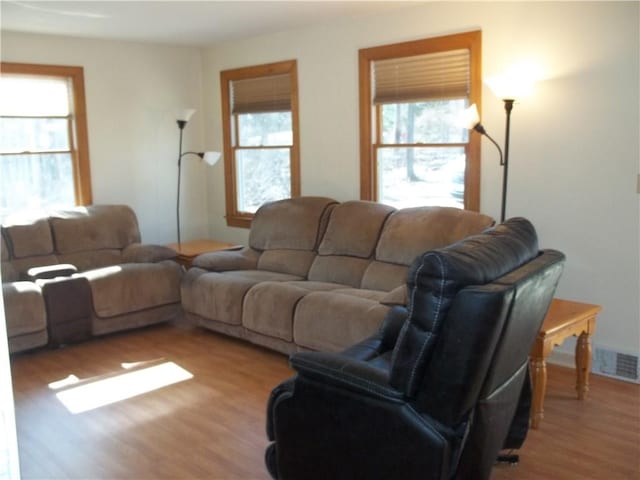 living area featuring light wood-style floors, plenty of natural light, and visible vents