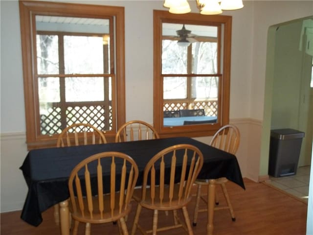 dining space with an inviting chandelier, arched walkways, and wood finished floors