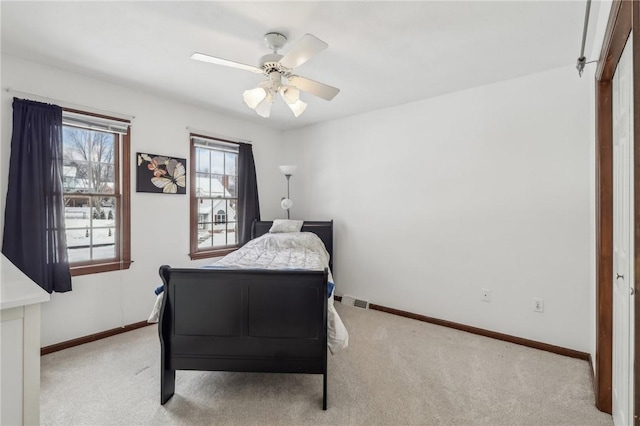 bedroom with light carpet, visible vents, baseboards, and a ceiling fan