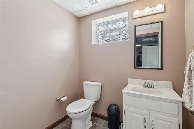 half bathroom with toilet, vanity, visible vents, baseboards, and tile patterned floors