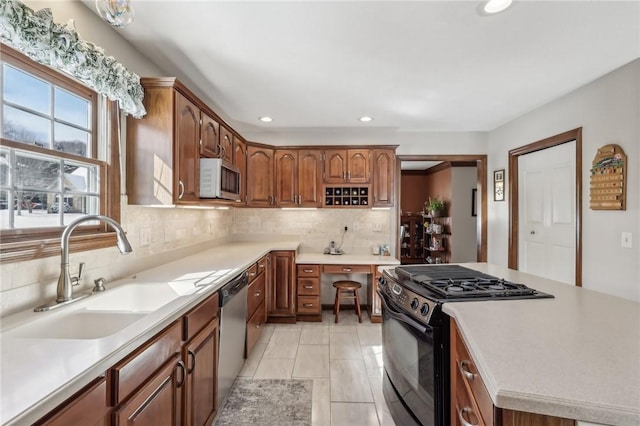 kitchen featuring a sink, light countertops, white microwave, and black range oven