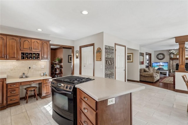 kitchen featuring open floor plan, light countertops, black gas range, and brown cabinets