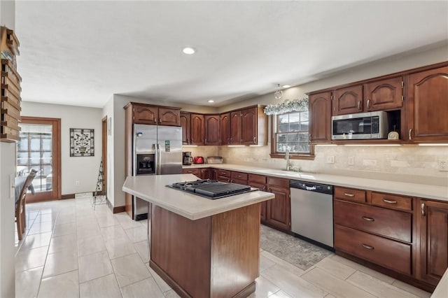 kitchen featuring decorative backsplash, a kitchen island, appliances with stainless steel finishes, light countertops, and a sink