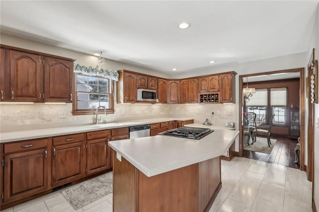 kitchen with tasteful backsplash, appliances with stainless steel finishes, brown cabinets, a center island, and light countertops