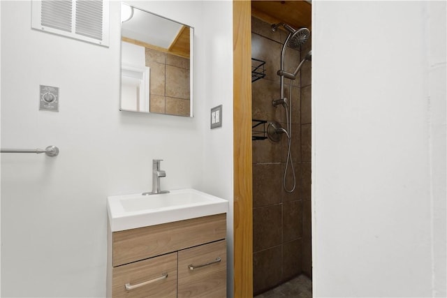 bathroom with tiled shower and vanity