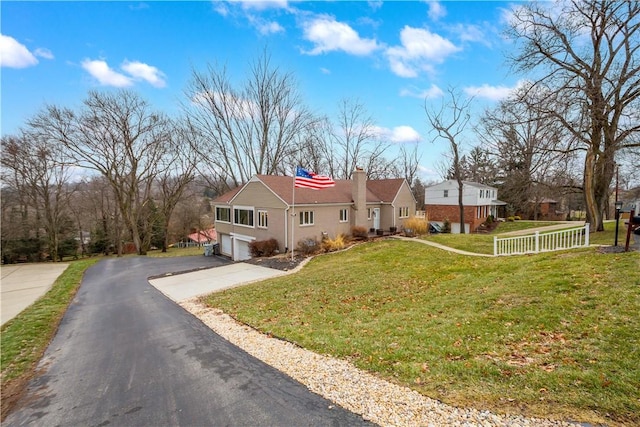 single story home with driveway, a chimney, an attached garage, fence, and a front yard