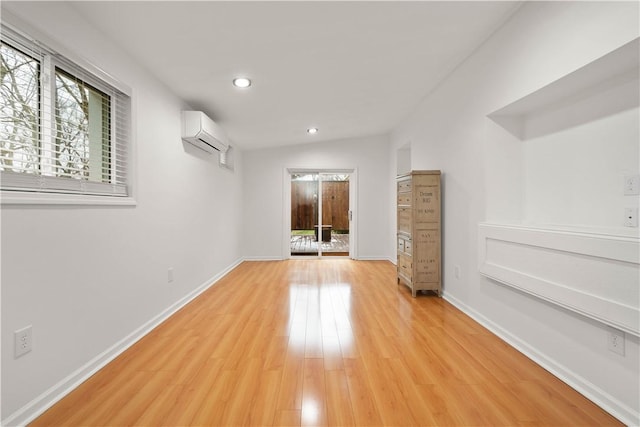 spare room featuring recessed lighting, light wood-style flooring, baseboards, and a wall mounted air conditioner