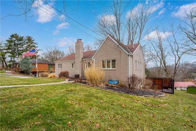 back of property featuring a yard, brick siding, and a chimney