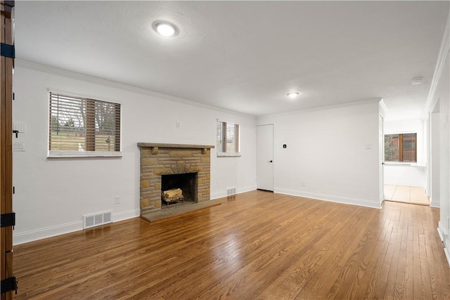 unfurnished living room featuring baseboards, visible vents, wood finished floors, crown molding, and a fireplace