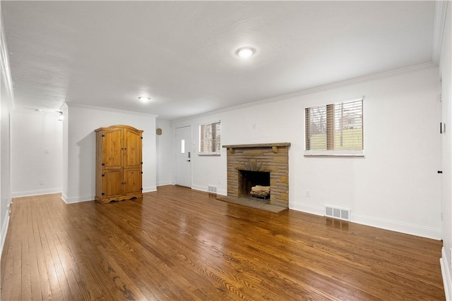 unfurnished living room featuring baseboards, crown molding, visible vents, and wood finished floors