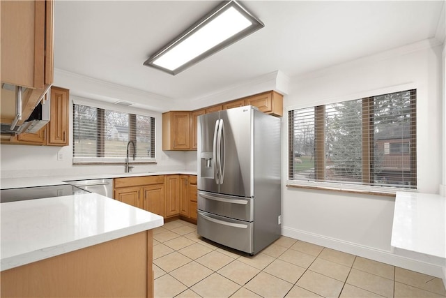 kitchen with light tile patterned floors, a sink, light countertops, appliances with stainless steel finishes, and ornamental molding