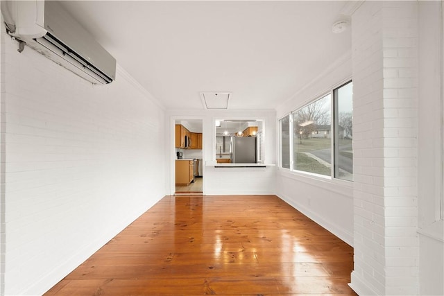 unfurnished living room featuring light wood-type flooring, crown molding, and a wall mounted AC