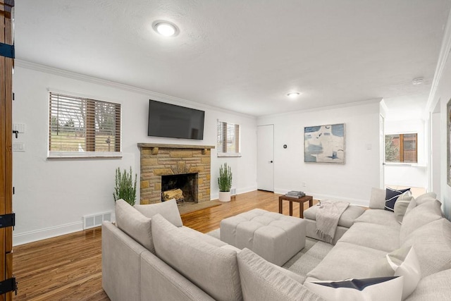 living room with light wood-style flooring, a fireplace, visible vents, and crown molding