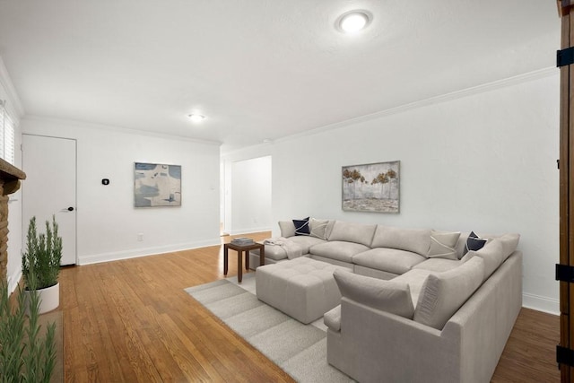 living room with ornamental molding, a fireplace with raised hearth, baseboards, and wood finished floors