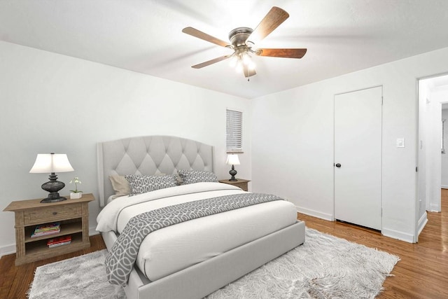 bedroom with a ceiling fan, baseboards, and wood finished floors