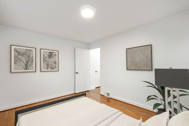 bedroom featuring baseboards, visible vents, and wood finished floors