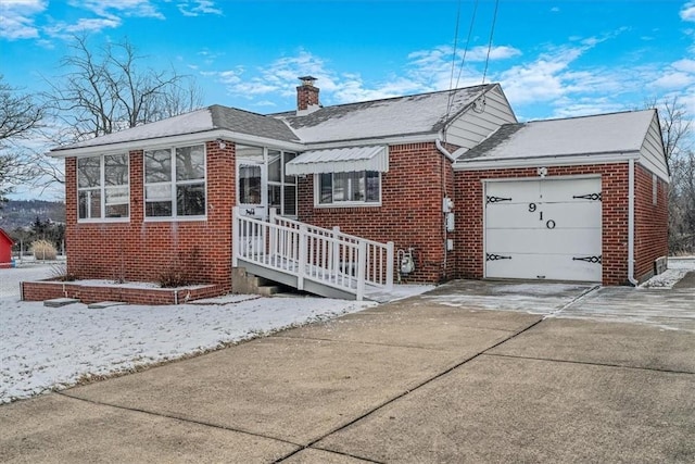 view of front of home featuring a garage, concrete driveway, brick siding, and a chimney