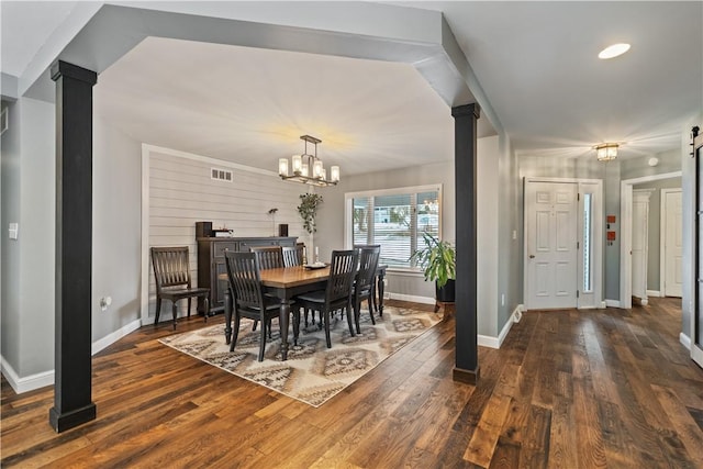 dining area with ornate columns, baseboards, dark wood-style floors, and a notable chandelier