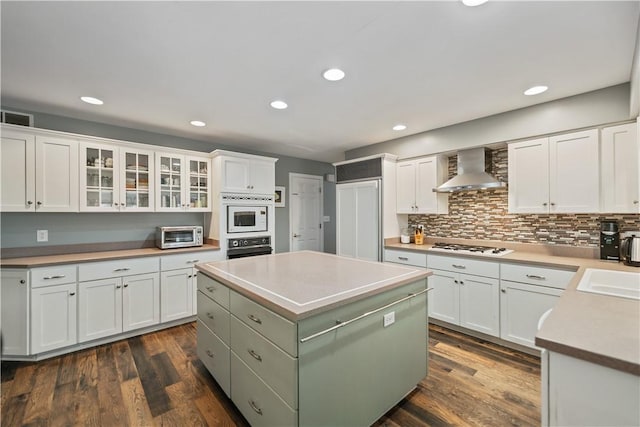 kitchen featuring wall chimney exhaust hood and white cabinetry