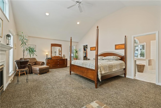 bedroom with high vaulted ceiling, a glass covered fireplace, light colored carpet, and a ceiling fan